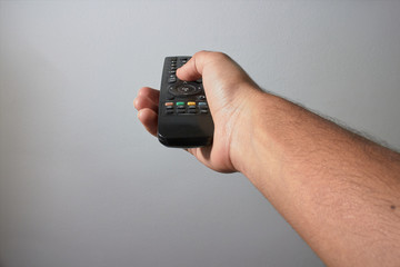 Fototapeta premium hand with remote control to change channel on white background