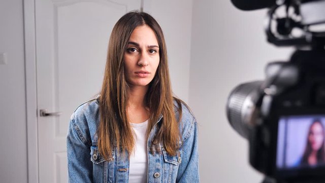 Blurry silhouette woman looking at the camera recording video at Home. Female smiles and is embarrassed