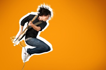 Male guitarist playing music on guitar and jump