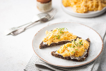 Scrambled egg sandwich with cream cheese on rye toast for breakfast on white background. Healthy breakfast or snack