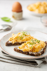 Scrambled egg sandwich with cream cheese on rye toast for breakfast on white background. Healthy breakfast or snack