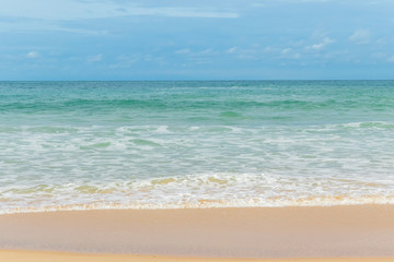 Fototapeta na wymiar sandy beach blue sky and white formy wave