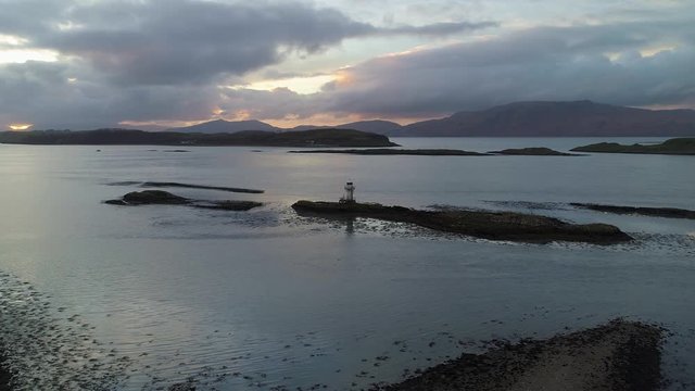 Lighthouse on rocky island, wide panoramic shot shows perspective down lake. Scotland, UK