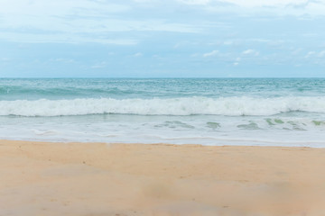 Fototapeta na wymiar sandy beach blue sky and white formy wave