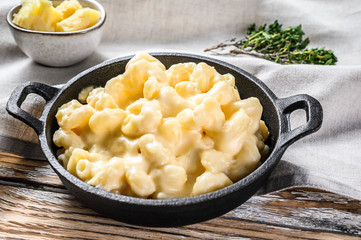 Mac and cheese, american style macaroni pasta in cheesy sauce.  White wooden background. Top view