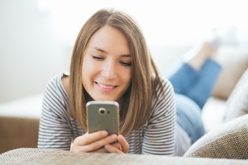 Beautiful young caucasian woman on  sofa using cell phone