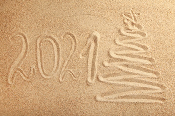 Fototapeta na wymiar 2021 new year text with christmas tree on sand background