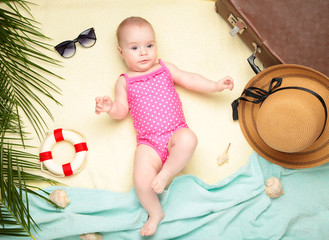 Cute baby girl with beach accessories on light background. Holidays at sea with baby, summer concept