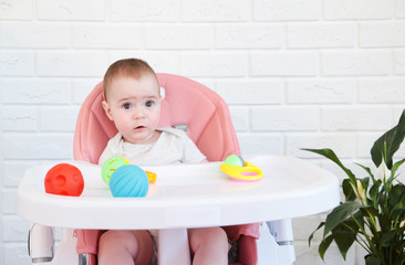 Cute baby girl playing a rattle in chair. Top view