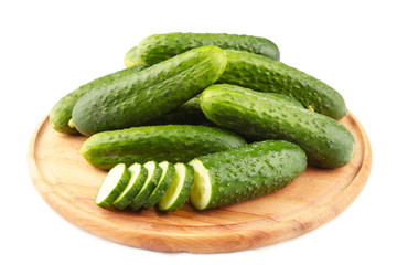 Fresh cucumbers on a wooden cutting board isolated on white background