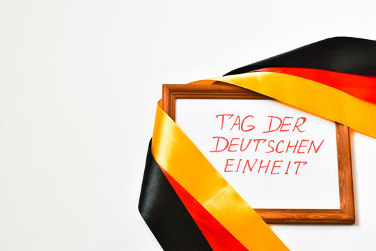 October 3, the day of German unity with national colors. Flag of Germany and the inscription German Unity Day on a white background. Place for text.