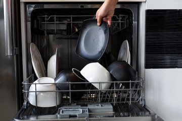 Loading dirty dishes in the dishwasher close up. a