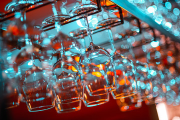Empty clean drink on hanger in bar. Red and turquoise hue, natural light of bar