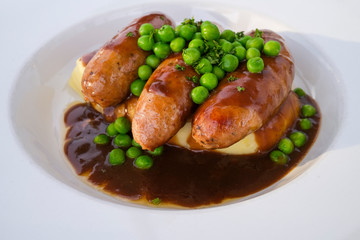 Sausages and mashed potatoes with green peas and gravy
