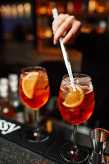 The barman decorates the alcoholic cocktail with a slice of  citrus using the pliers