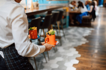 The waiter in the restaurant carries mugs with hot drinks. view from the back