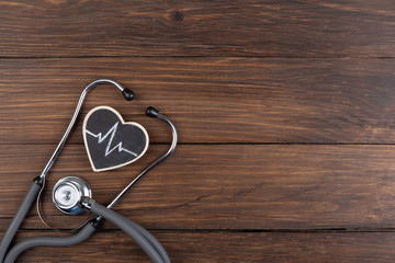 Workplace of a doctor. Stethoscope and little heart on wooden desk background