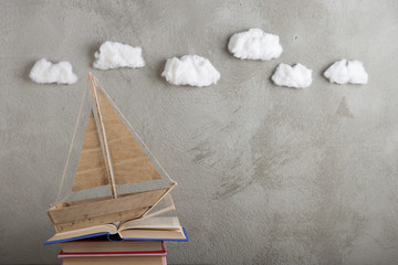 Education is a journey concept, toy boat and books like a sea waves on the wooden table,...