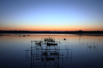 Fish trap and calm blue lake at dawn