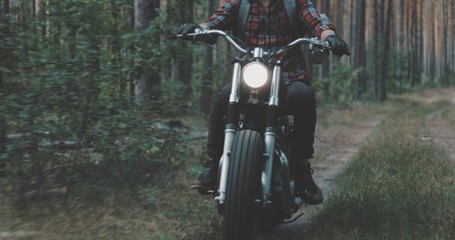 Young rider driving motorcycle on forest road