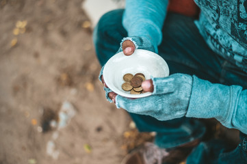 Man sitting beggar with a cup and money.