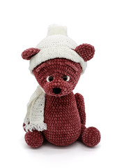 Knitted toy bear in a hat and scarf on a white background