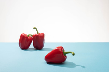 fresh red bell peppers on blue surface on white background