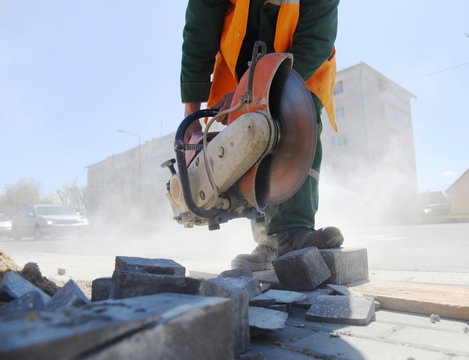 A man puts a circular saw, road repairs.