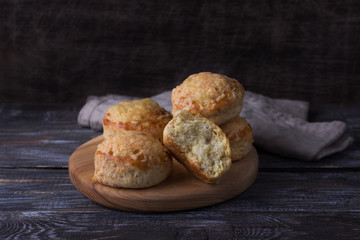 Homemade freshly baked scones with cheese and herbs on wooden board on wooden table. Traditional english buns