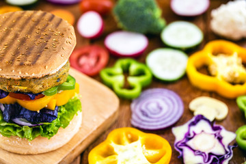 vegetarian burger, home made. with vegetables, fiber and proteins. Gourmet snack with vegetables in the background on a rustic wooden table.
