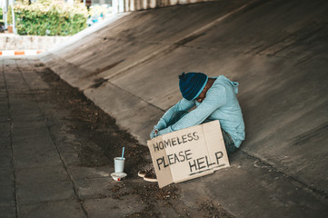 The beggars sit under the bridge with a homeless message. Please help.