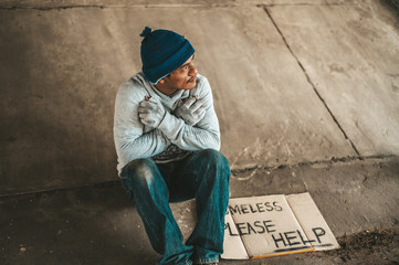 The beggars sit under the bridge with a homeless message. Please help.