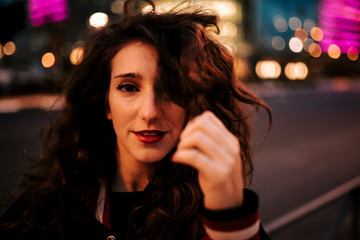 Beautiful spanish woman listening to music with earphones and smart phone outdoors in the night city