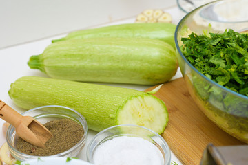 step-by-step recipe to cook pancakes of zucchini and greens on a light background. with the addition of eggs, flour, garlic, pepper. the view from the top