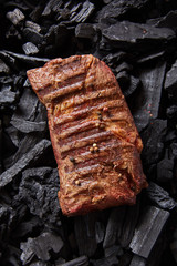 top view of fresh grilled tasty steak on black coals