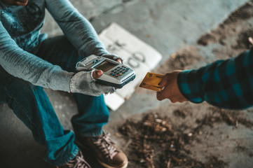 Beggars sitting under the overpass with a credit card and credit card swipe machine