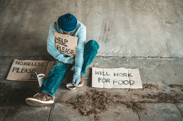 Begging under the bridge with a cup containing coins and instant noodles