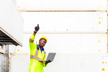 Foreman using laptop computer in the port of loading goods. Foreman showing thumbs up on Forklifts in the Industrial Container Cargo freight ship.