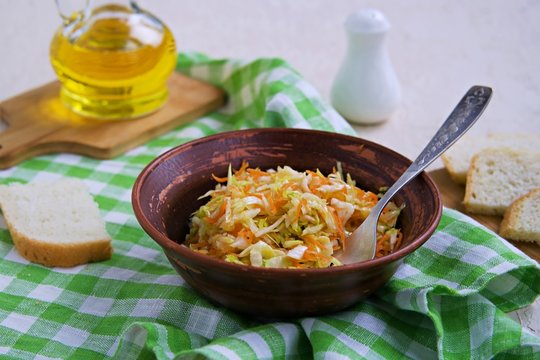 Coleslaw salad of fresh cabbage and carrots in a brown clay bowl on a light concrete background. Healthy food. Vegetarian recipes.
