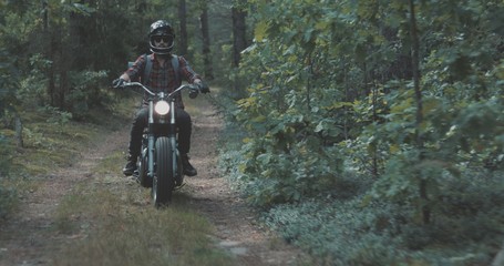 Young rider driving motorcycle on forest road