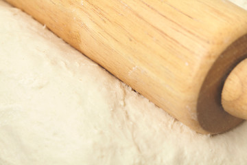 Dough and wood rolling pin on clean black background Close up