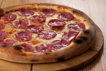 hearty italian pizza on a wooden board. cheese pizza with salami sausage