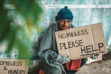 Beggars sitting on the street with homeless messages please help.