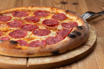 hearty italian pizza on a wooden board. cheese pizza with salami sausage