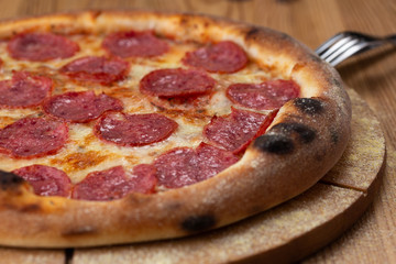 hearty italian pizza on a wooden board. cheese pizza with salami sausage
