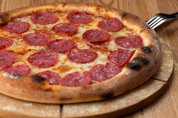 hearty italian pizza on a wooden board. cheese pizza with salami sausage