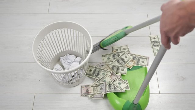 cleaning with broom of dollar bills and throwing it in the trash bin