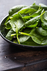 Fresh baby spinach on a plate. Juicy spinach leaves. Diet concept. Vegan food.