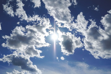 Beautiful skyscape with many cumulonimbus clouds and shiny sun in the middle