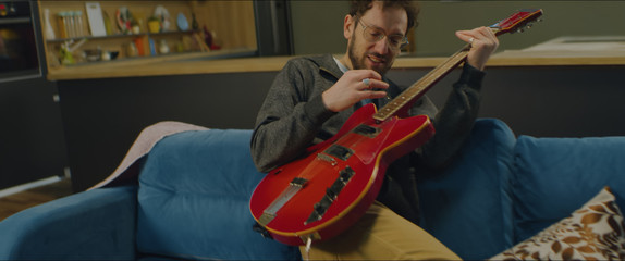 DX MED aucasian male going crazy while playing his electric guitar at home, practicing during...